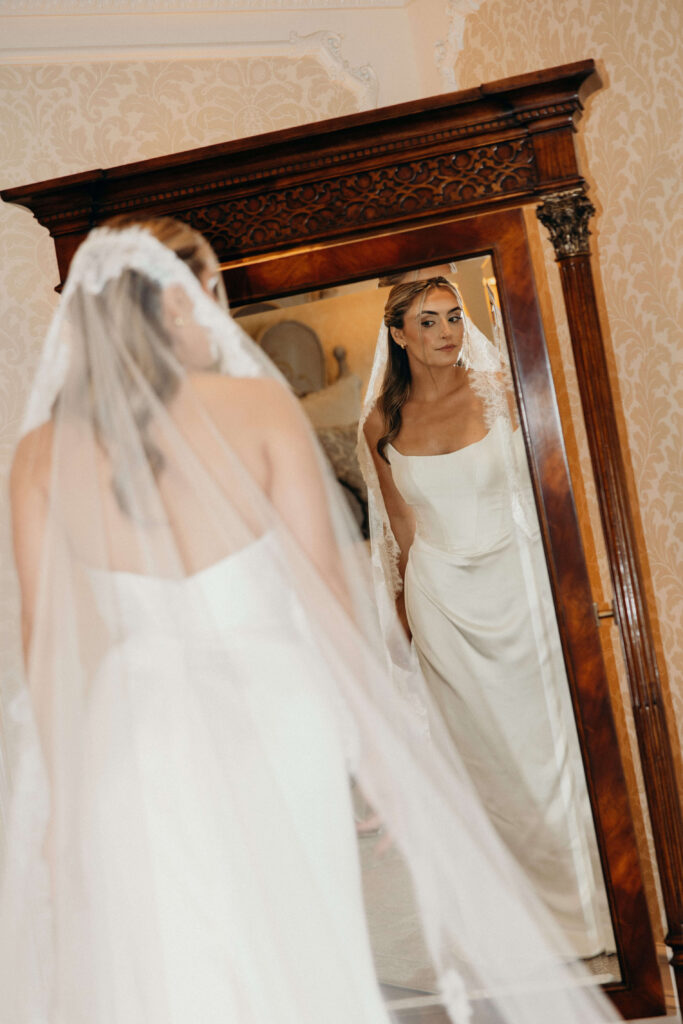Bride Shay admiring her reflection while wearing her wedding dress and veil at The Ashford Estate