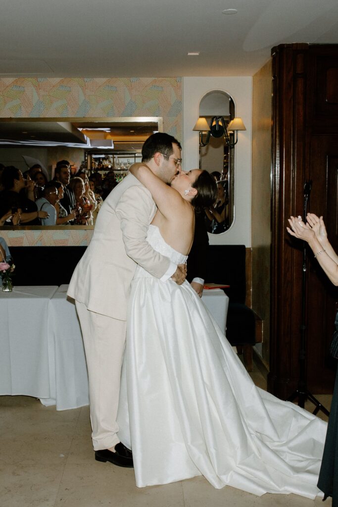 Newlyweds share a kiss surrounded by their guests at Le Bilboquet, captured by a New York wedding photographer