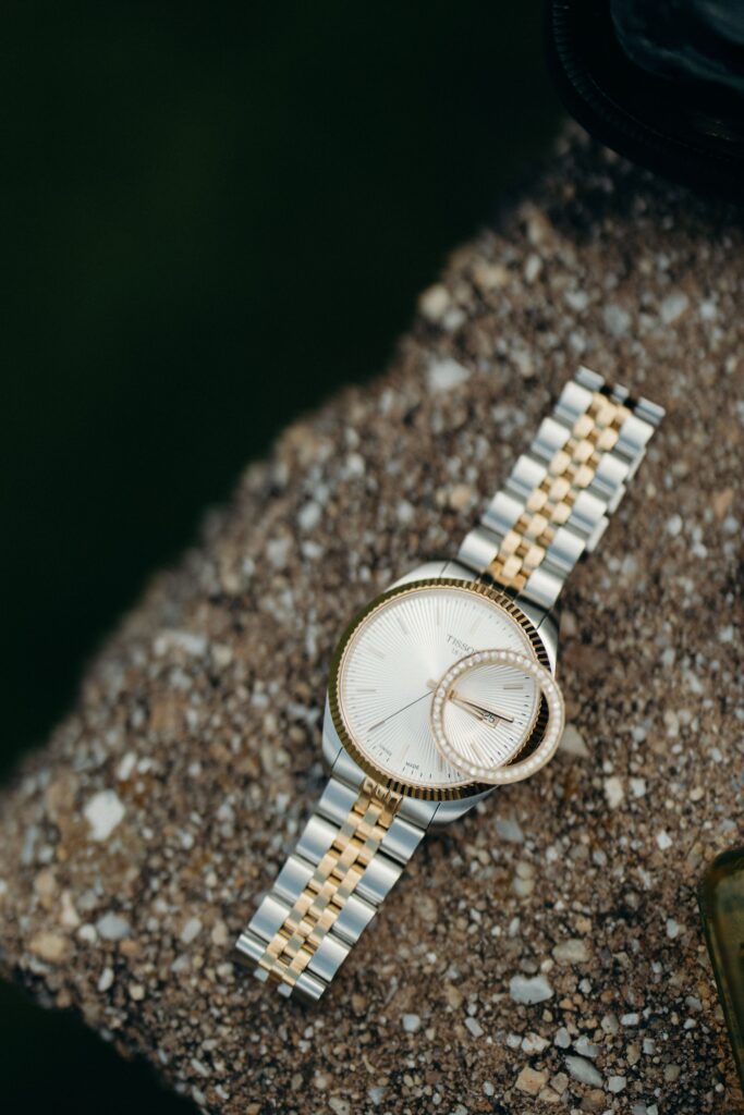 Silver and gold watch with a wedding band resting on the watch face at Perona Farms