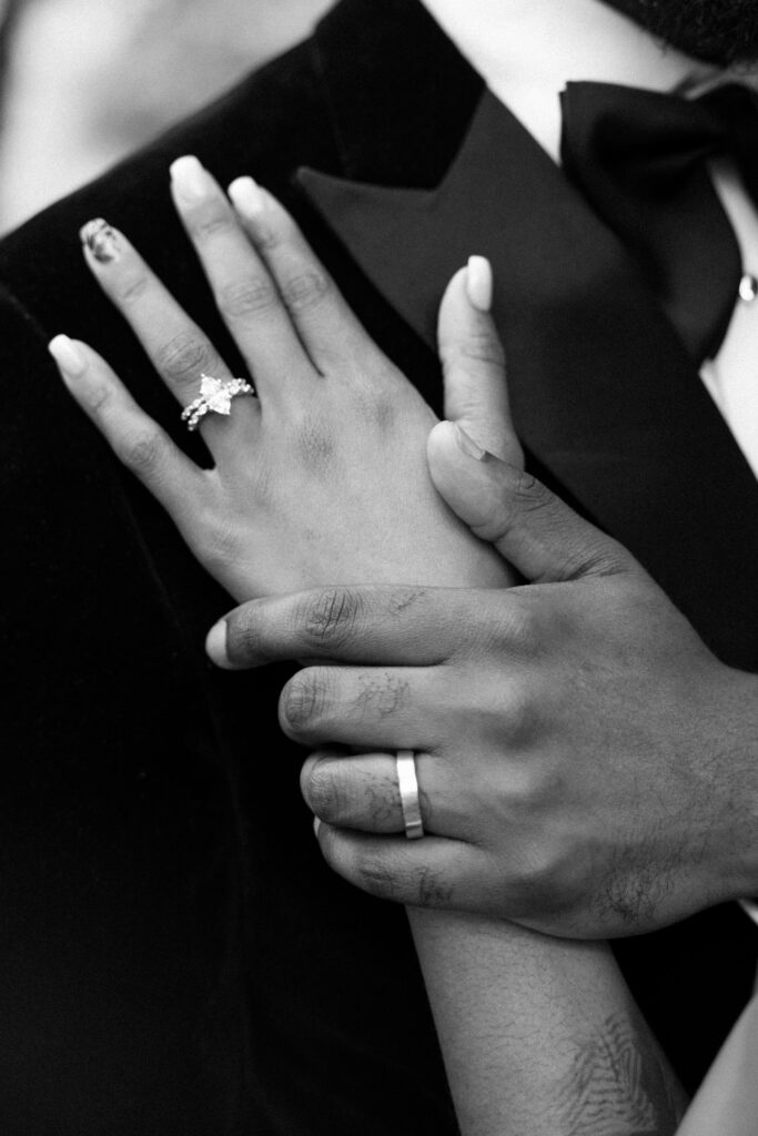 Close-up black and white shot of a groom holding the bride's hand showing off her engagement ring at Perona Farms