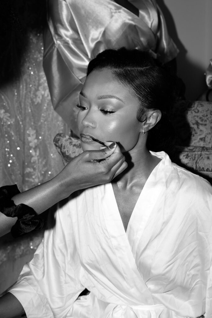 Black and white close-up of a makeup artist applying lip product on the bride at Perona Farms