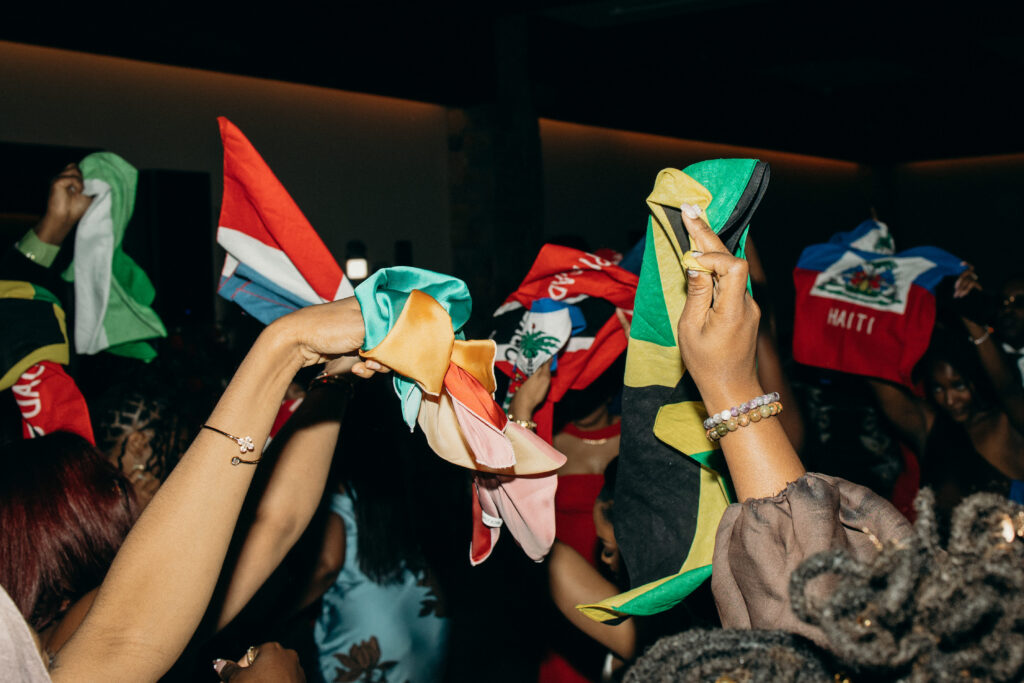 Wedding guests waving colorful flags on the dance floor during a reception at Perona Farms