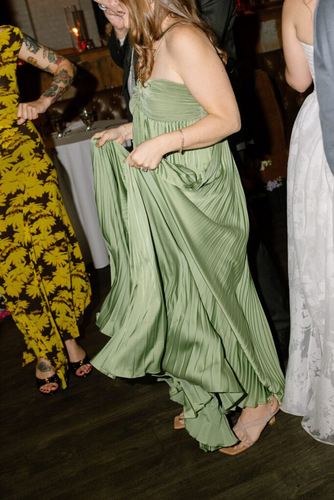 Wedding guest in a pleated green dress dancing at Battello