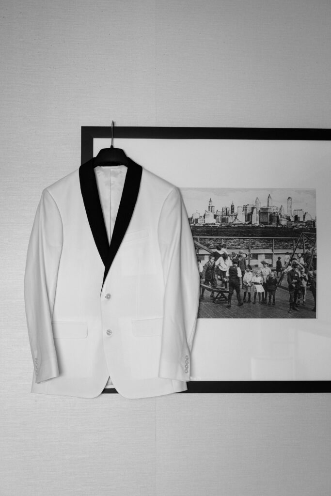 White tuxedo jacket with a black lapel hanging on a wall before a wedding at Battello