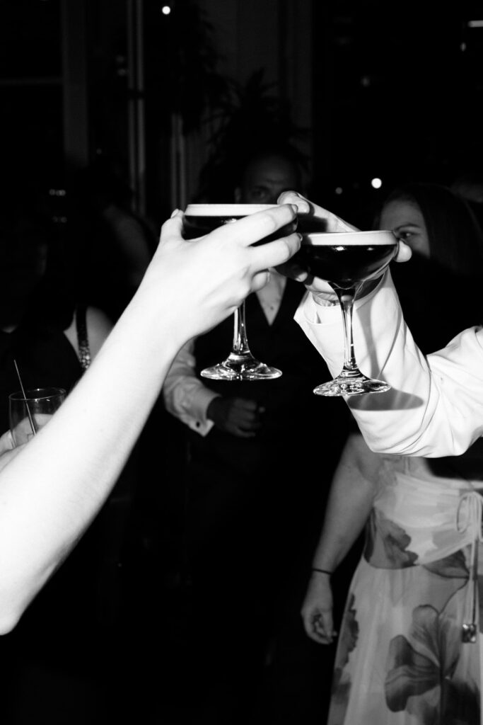 Close-up of wedding guests clinking cocktail glasses in a toast at Battello