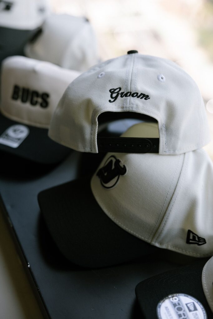 Custom baseball hats including one embroidered with Groom on display before a wedding at Battello