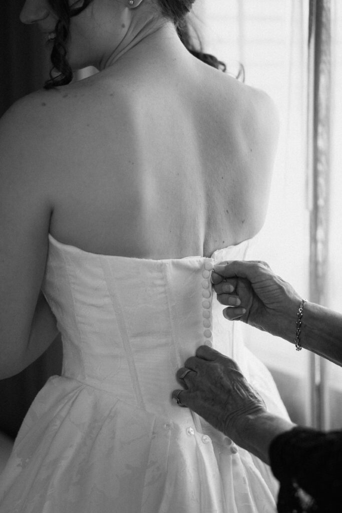 Close-up of a bride getting her strapless wedding dress buttoned up at Battello