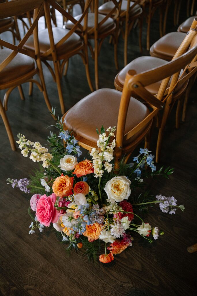 Bright floral arrangement on the floor next to wooden chairs at Battello