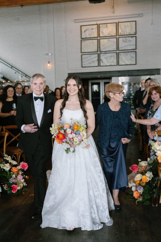 Bride walking down the aisle with her parents at Battello