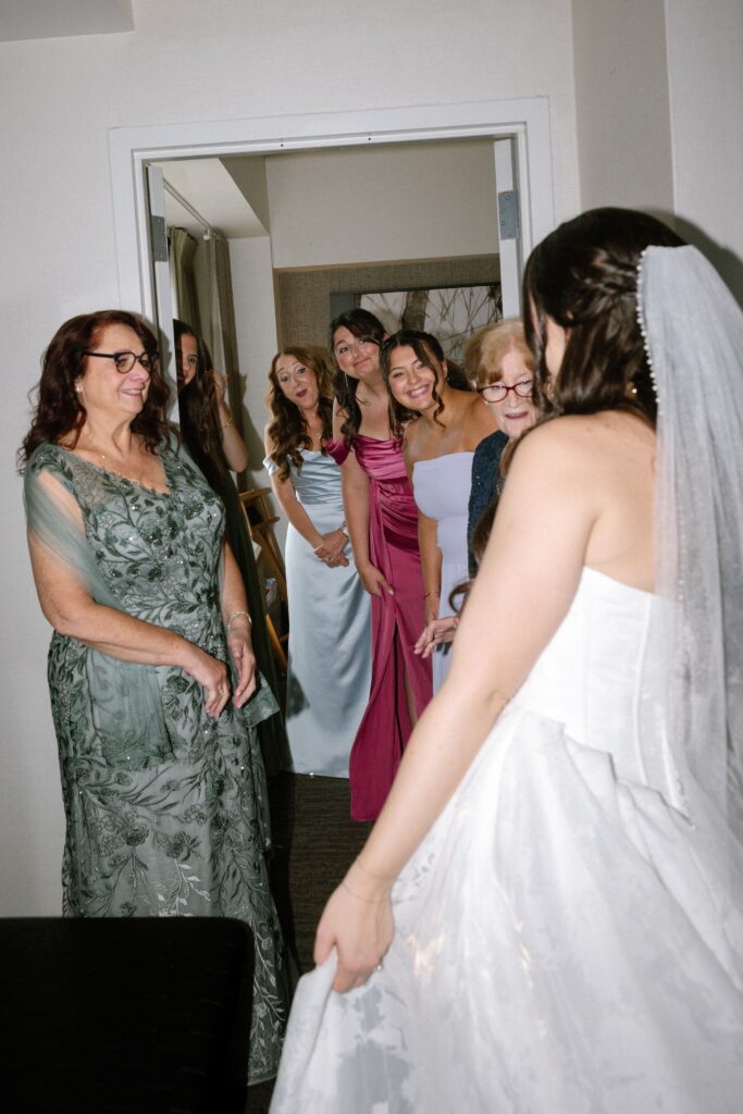 Bride revealing her wedding dress to her mother and bridesmaids prior to a wedding at Battello