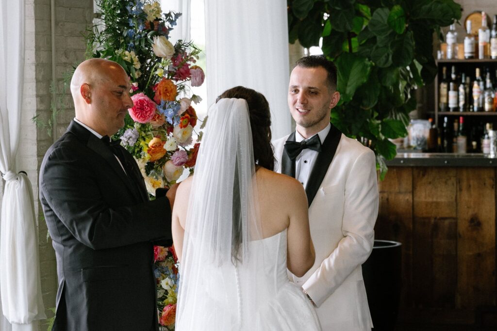 Groom smiling at the bride during the ceremony at Battello