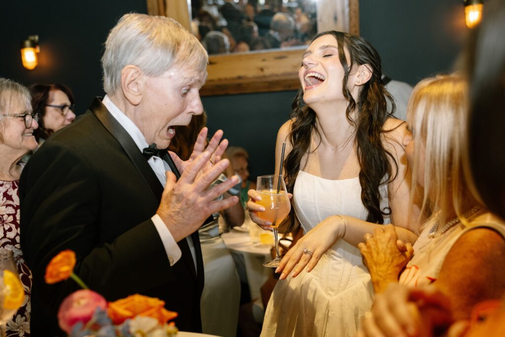 Bride holding a drink and laughing with guests at Battello