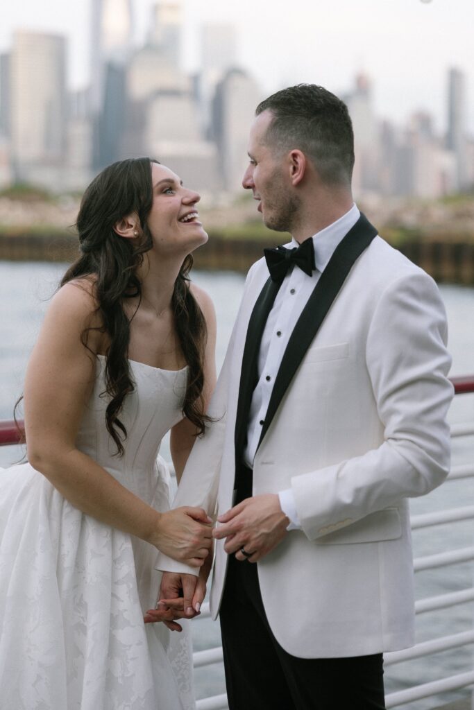 Bride and groom laughing together outdoors with the skyline behind them at Battello