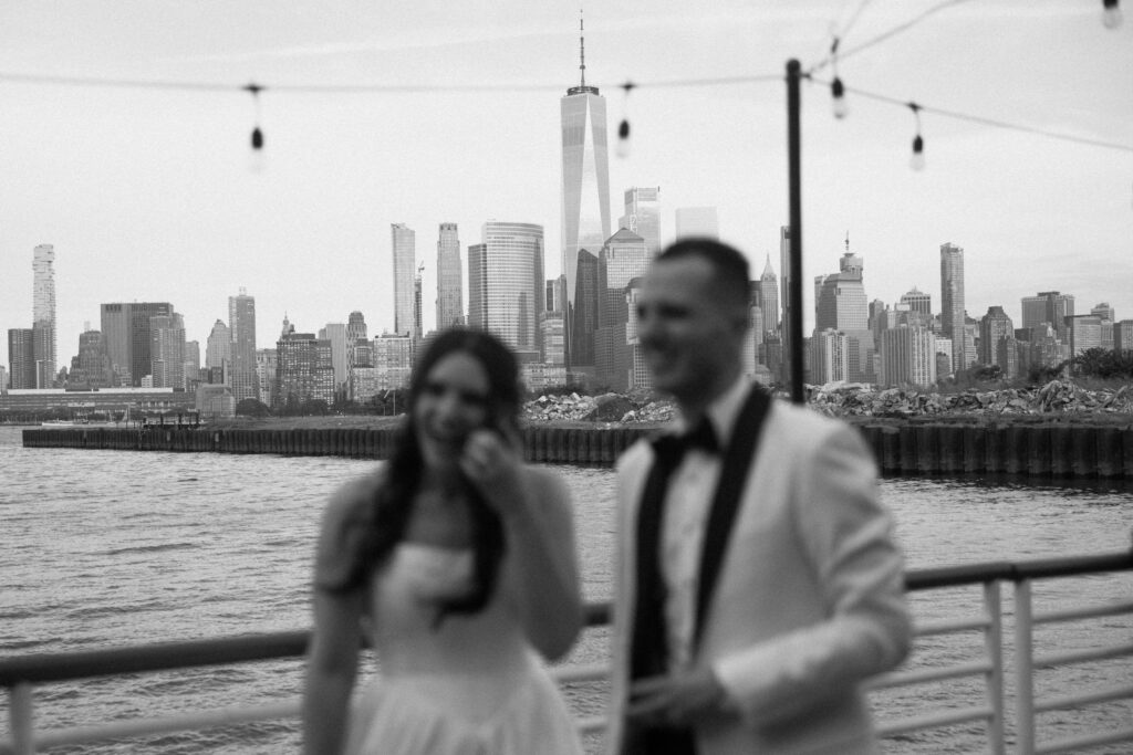 Black and white shot of a bride and groom on the pier with the city skyline at Battello