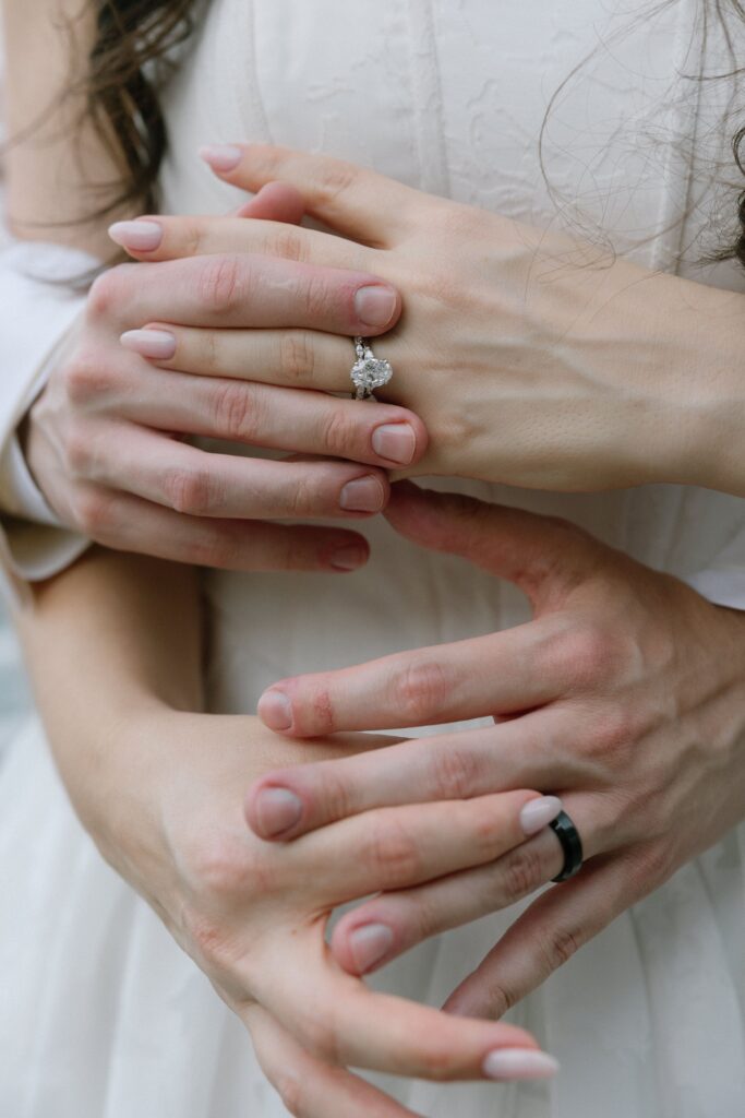 Close-up of a bride and groom holding hands and showing their wedding rings at Battello