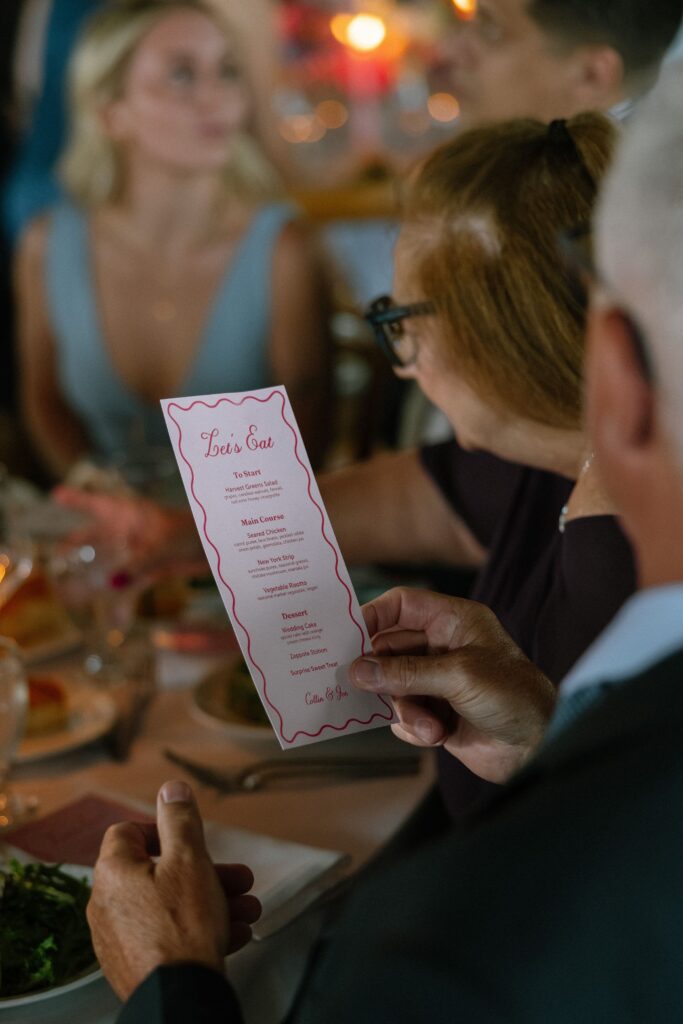 A close-up of a guest's hand holding a printed reception menu at Battello