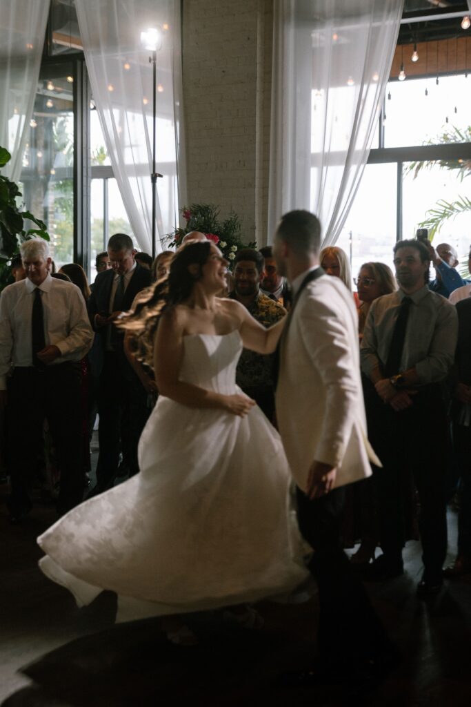 Newlywed couple dancing their first dance in the middle of a crowded dance floor at Battello