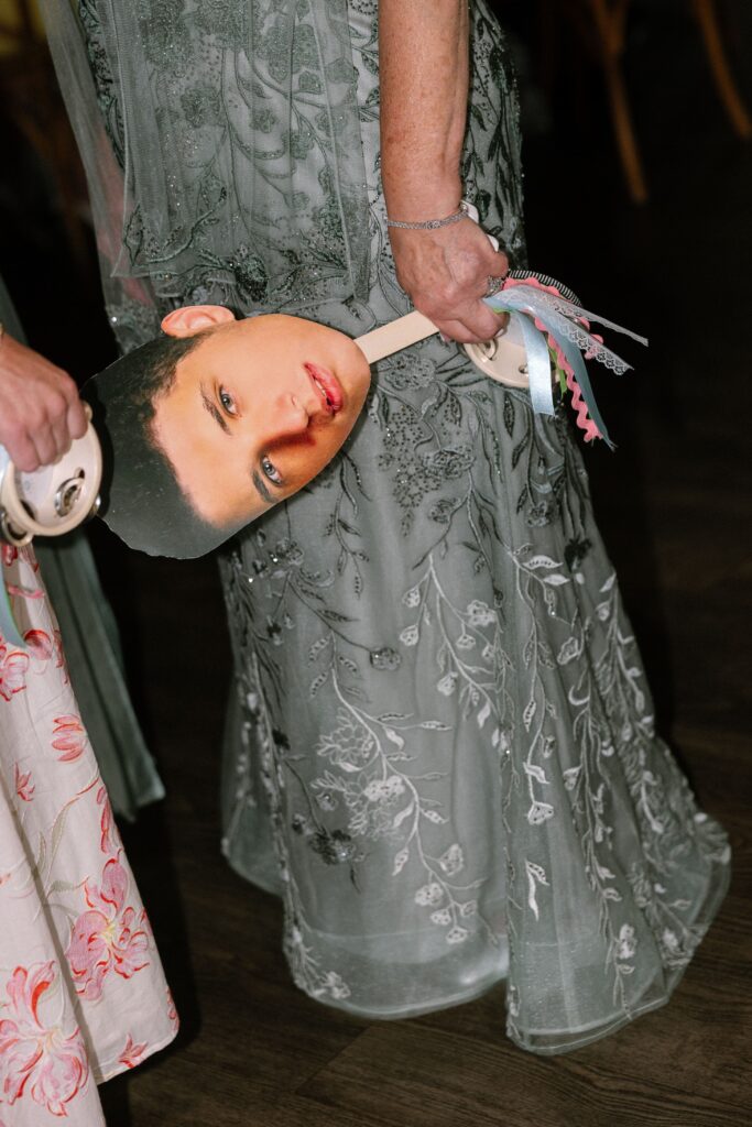 Close-up of a guest holding a cardboard cutout of the groom's head at Battello